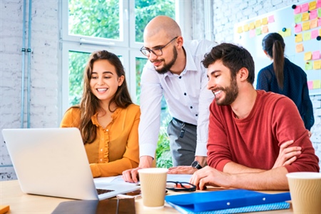 Tres personas reunidas frente a un portátil, ideal para contenidos sobre emprendimiento, innovación y trabajo colaborativo.