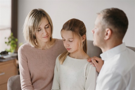 Padres consolando a su hija en un momento de dificultad, reflejando apoyo y comprensión.
